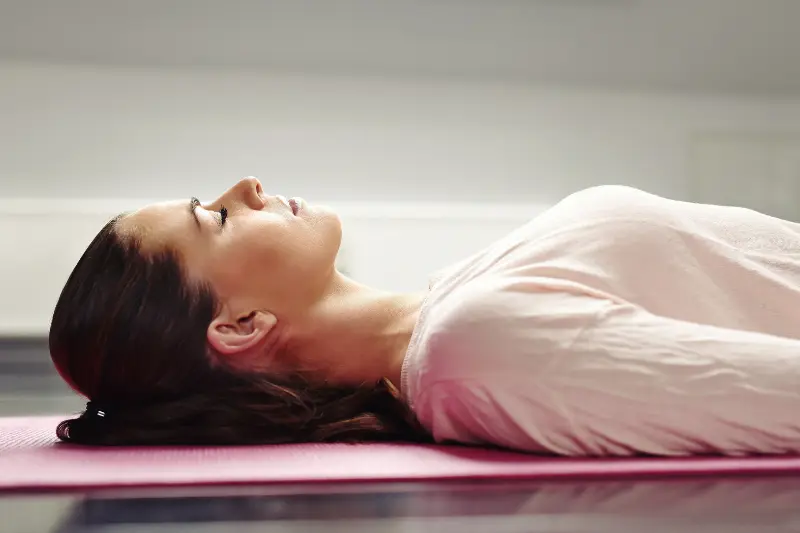 Femme allongée sur un tapis de yoga pendant une relaxation