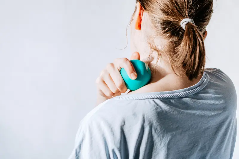 Femme utilisant une balle thérapeutique sur le haut du dos