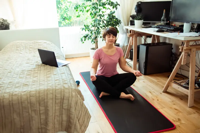 Femme méditant sur un tapis de yoga dans une chambre